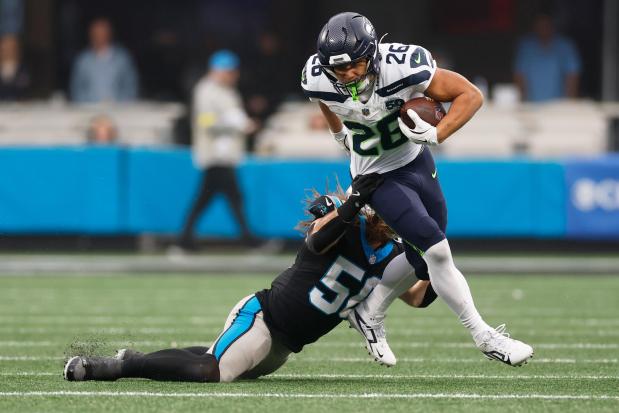 Seattle Seahawks running back Zach Charbonnet. is tackled by Carolina Panthers linebacker Christian Rozeboom during the second half of an NFL football game, Sunday, Dec. 28, 2025, in Charlotte, N.C. (AP Photo/Rusty Jones)