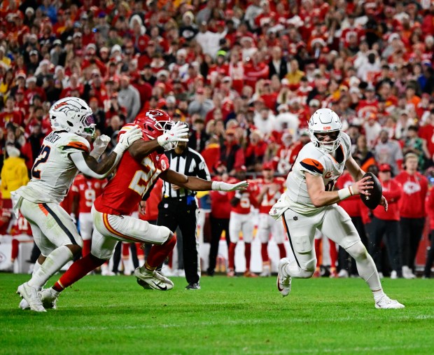 Denver Broncos quarterback Bo Nix (10) gets a block from RJ Harvey (12) while scrambling away from Kansas City Chiefs safety Jaden Hicks (21) at GEHA Field at Arrowhead Stadium in Kansas City, Missouri on Thursday, Dec. 25, 2025. (Photo by Andy Cross/The Denver Post)