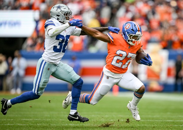 J.K. Dobbins (27) of the Denver Broncos stiff arms Alijah Clark (38) of the Dallas Cowboys during the first quarter at Empower Field at Mile High in Denver on Sunday, Oct. 26, 2025. (Photo by AAron Ontiveroz/The Denver Post)