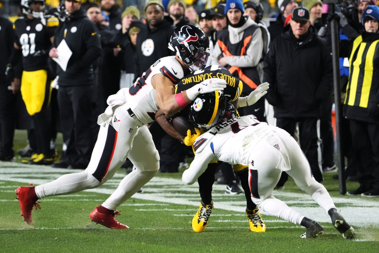 Houston Texans linebacker Henry To’oTo’o (left) and cornerback Kamari Lassiter tackle Pittsburgh Steelers wide receiver Marquez Valdes-Scantling during an NFL playoff game on Monday, Jan. 12, 2026, at Acrisure Stadium in Pittsburgh.