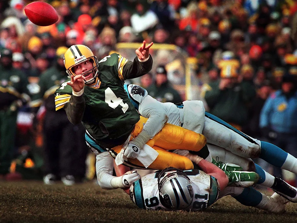 Green Bay Packers quarterback Brett Favre releases a shuttle pass to Dorsey Levens for a first down while in the grasp of Carolina Panthers linebacker Kevin Greene.
