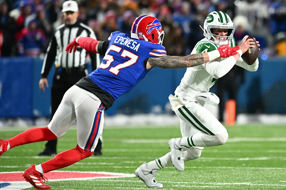 Jan 4, 2026; Orchard Park, New York, USA; New York Jets quarterback Brady Cook (4) scrambles with the ball under pressure from Buffalo Bills defensive end AJ Epenesa (57) during the first half at Highmark Stadium. Mandatory Credit: Mark Konezny-Imagn Images