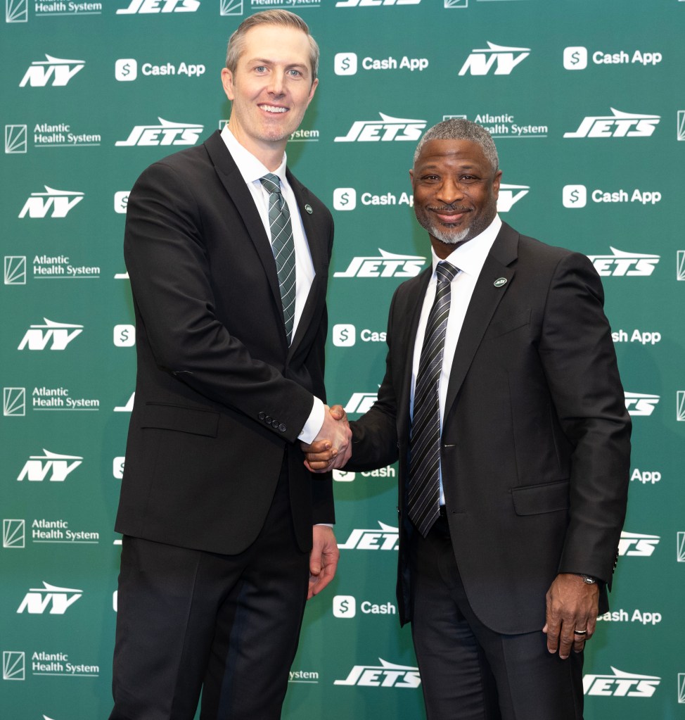 Aaron Glenn and Darren Mougey shaking hands at a press conference.