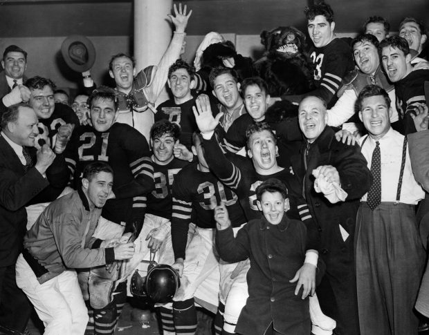 The Chicago Bears' locker room was a scene of joy as Owner/Coach George Halas, far left, led players, staff members and well wishers in a rousing cheer after the team's 33 to 14 victory over the Green Bay Packers at Wrigley Field on Dec. 14, 1941, in a playoff for the Western Division National league title. (Chicago Tribune historical photo) 
