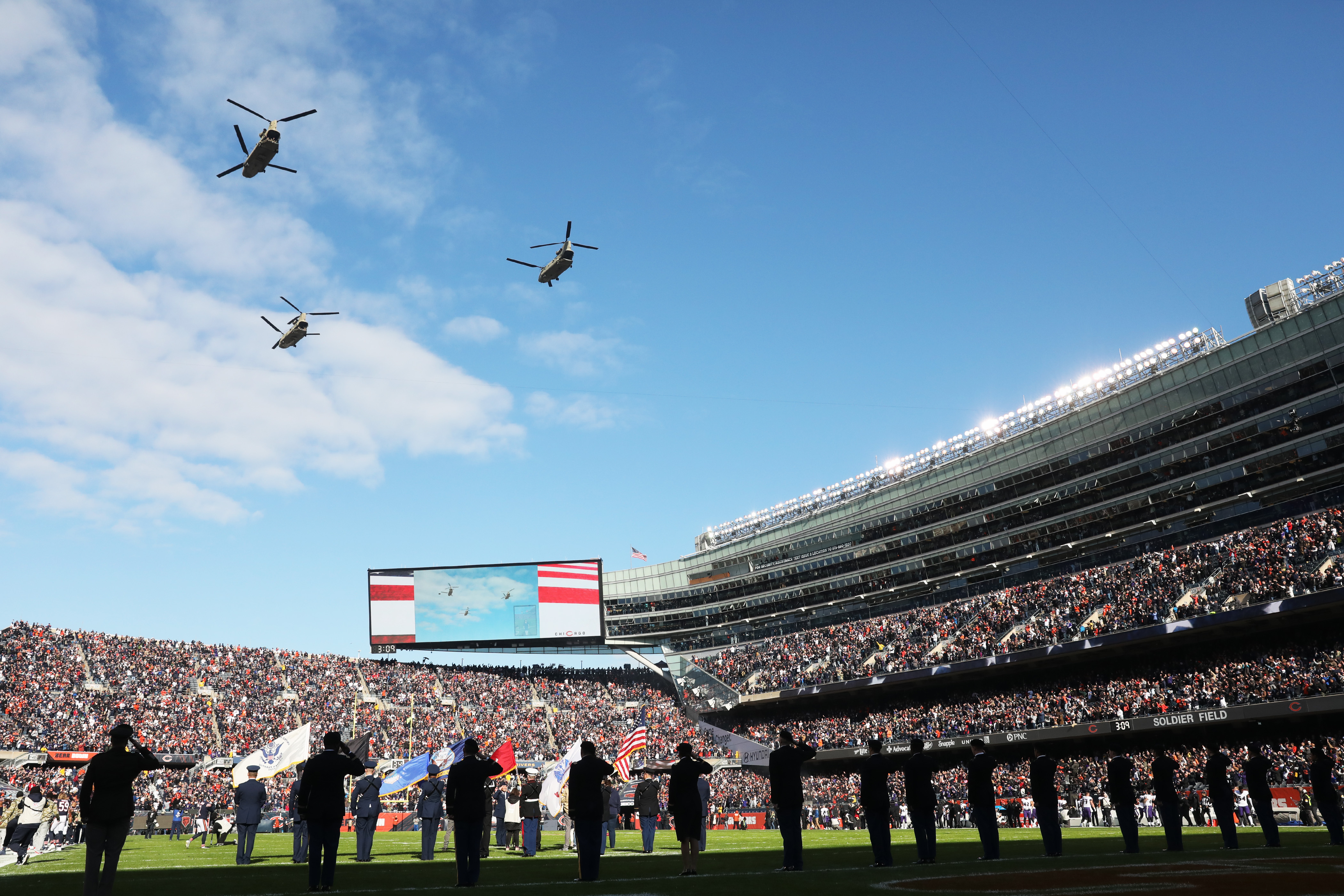 Military helicopters fly overhead during a ceremony before a Bears-Ravens...