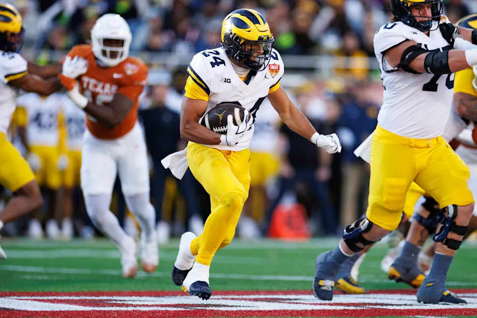 Michigan Wolverines running back Bryson Kuzdzal (24) rushes with the ball against the Texas Longhorns during the first half at Camping World Stadium in Orlando, Florida, on Wednesday, Dec. 31, 2025.