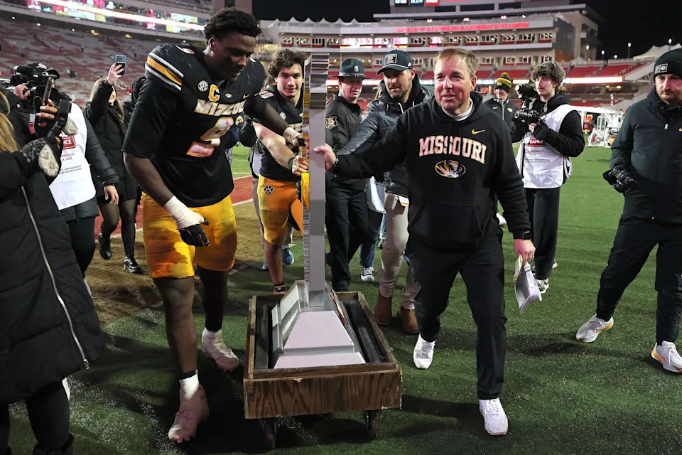 Nov 29, 2025; Fayetteville, Arkansas, USA; Missouri Tigers head coach Eli Drinkwitz celebrates with defensive end Zion Young (9) and the Battle Line trophy after a game against the Arkansas Razorbacks at Donald W. Reynolds Razorback Stadium. Missouri won 31-17. Mandatory Credit: Nelson Chenault-Imagn Images