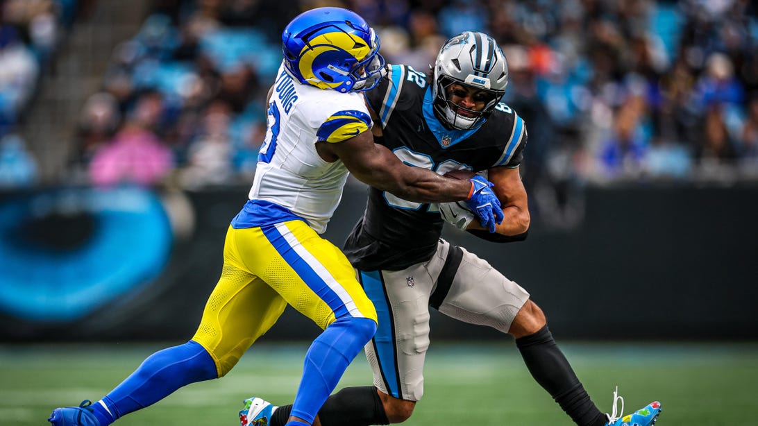 CHARLOTTE, NORTH CAROLINA - NOVEMBER 30: Tommy Tremble #82 of the Carolina Panthers is tackled by Byron Young #0 of the Los Angeles Rams during the second half of an NFL game at Bank of America Stadium on November 30, 2025 in Charlotte, North Carolina.