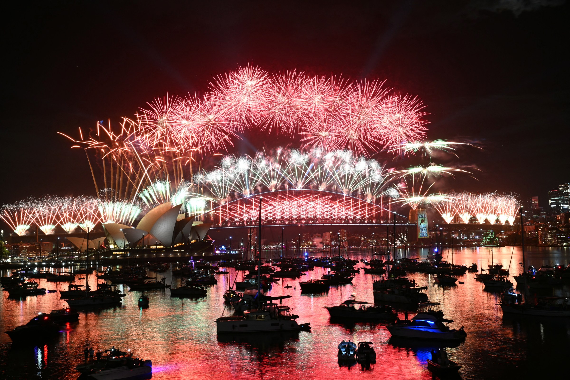 TOPSHOT - Fireworks light up the midnight sky over Sydney Harbour Bridge and Sydney Opera House during New Year’s Day celebrations in Sydney on January 1, 2026. (Photo by Saeed KHAN / AFP via Getty Images)