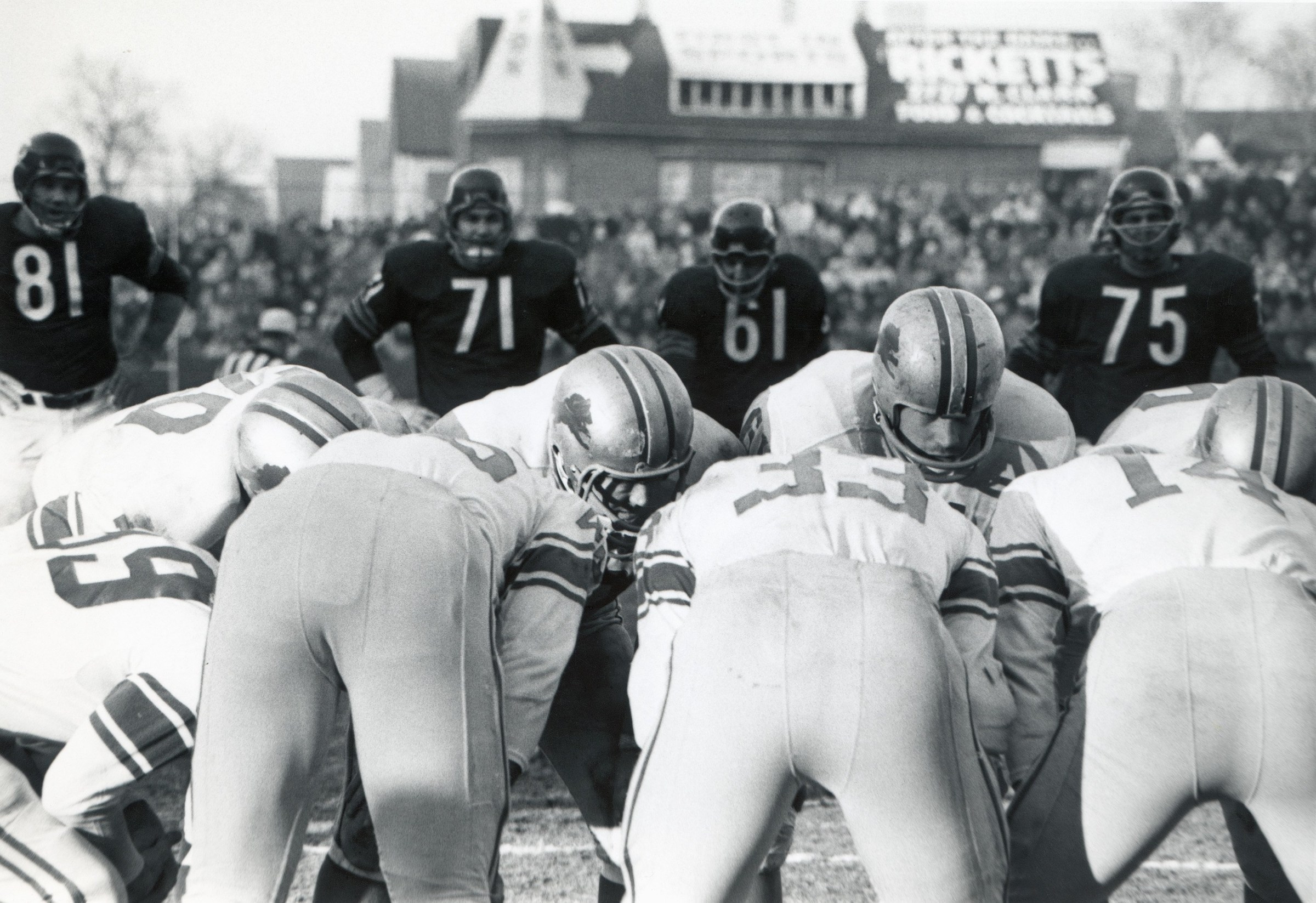 CHICAGO - CIRCA 1960S: The Detroit Lions offense huddles as Doug Atkins #81, Earl Leggett #71, Bill George #61 and Fred Williams #75 of the Chicago Bears look on during a circa 1960s game at Soldier Field in Chicago, Illinois. (Photo by Robert Riger/Getty Images)