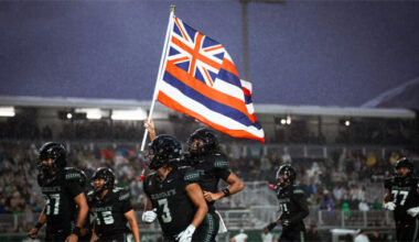 Football players carrying the Hawaiian flag