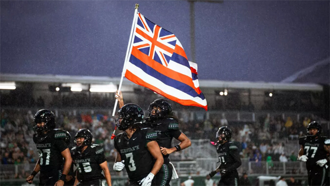 Football players carrying the Hawaiian flag