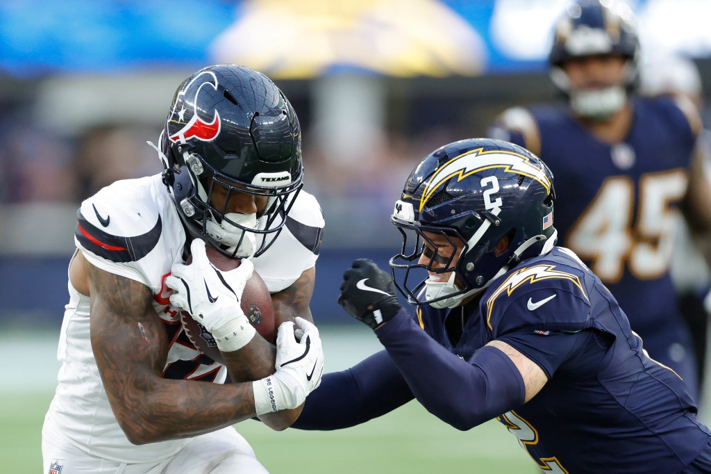 Nico Collins of the Houston Texans running with the ball against Elijah Molden of the Los Angeles Chargers.