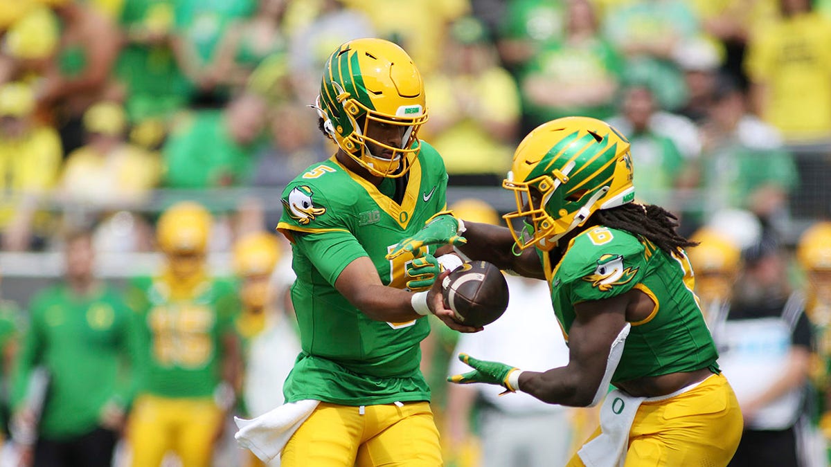 Dante Moore hands the ball off