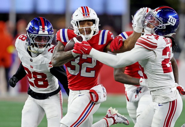 New England Patriots running back TreVeyon Henderson (32) pushes New York Giants safety Dane Belton (24) as he runs for extra yards during the second half of an NFL game at Gillette Stadium. (Photo By Matt Stone/Boston Herald)