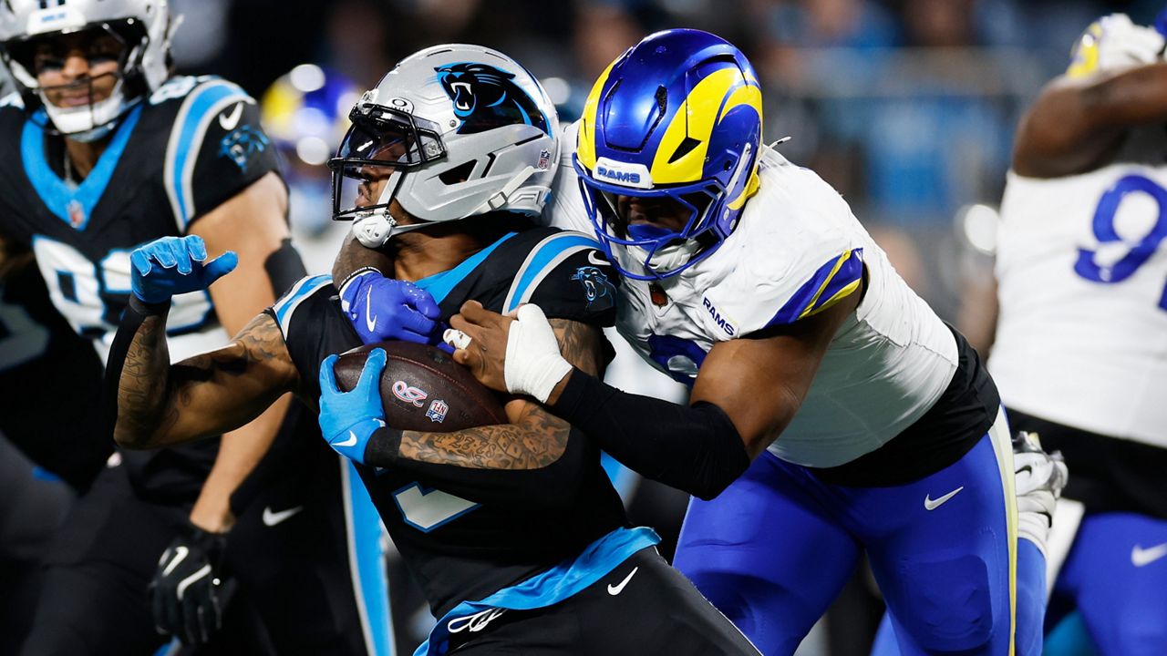 Carolina Panthers running back Rico Dowdle (5) is tackled by Los Angeles Rams linebacker Jared Verse during the first half of an NFL wild-card playoff football game, Saturday, Jan. 10, 2026, in Charlotte, N.C. (AP Photo/Rusty Jones)