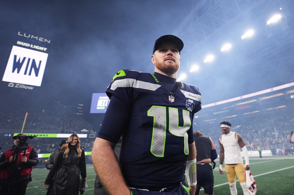 Seattle Seahawks quarterback Sam Darnold walks on the field after an NFL playoff game.