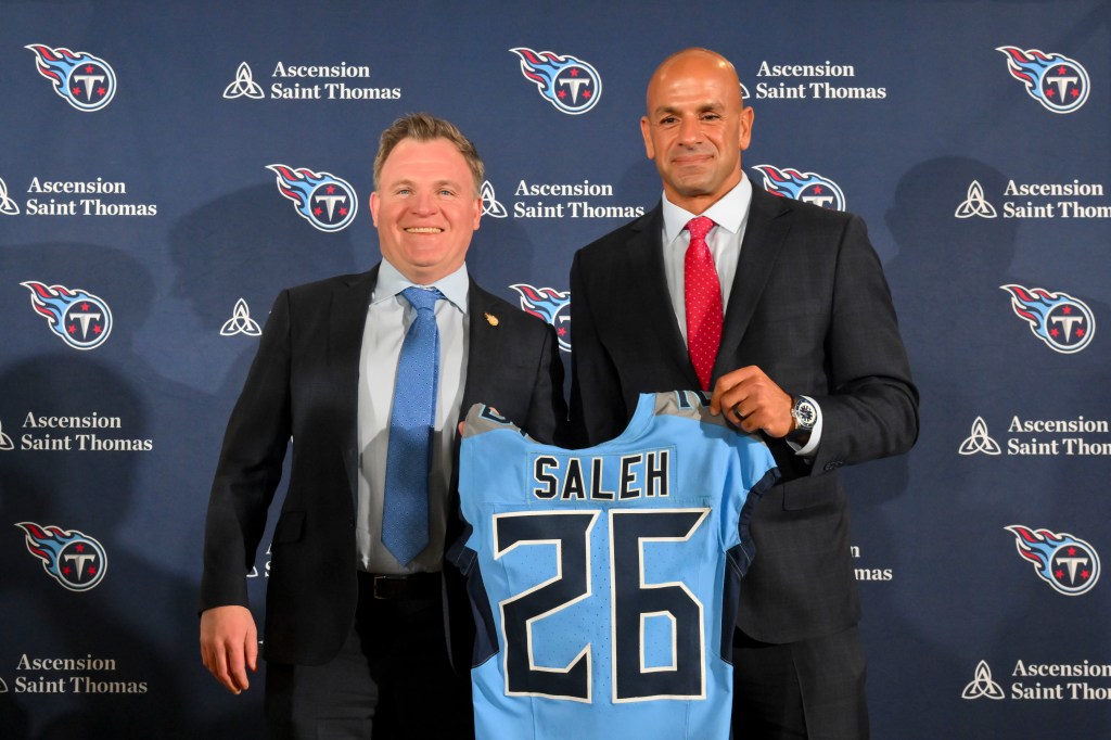 Tennessee Titans general manager Mike Borgonzi and head coach Robert Saleh holding up a Titans jersey during a press conference.