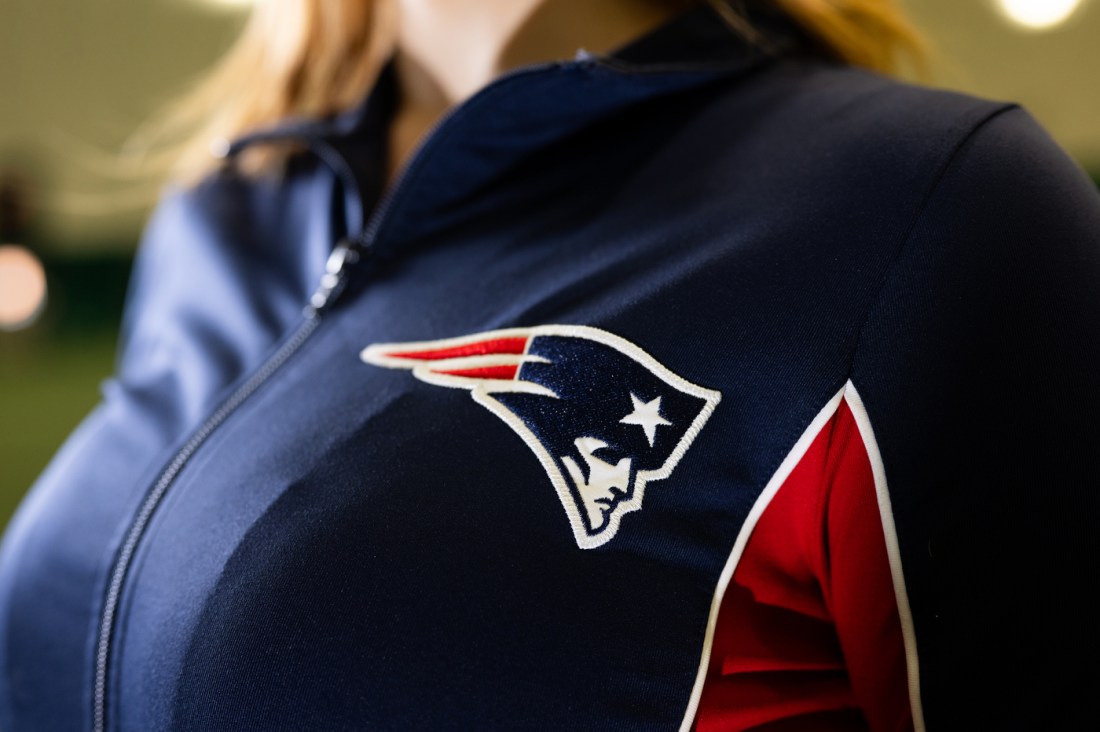 A closeup of the Patriots logo embroidered on the front of Lana's uniform