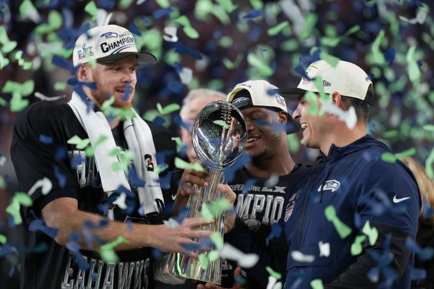 From left, Seattle Seahawks quarterback Sam Darnold, running back Kenneth Walker III and head coach Mike Macdonald hold the Lombardi Trophy after winning Super Bowl LX on Sunday, February 8.
