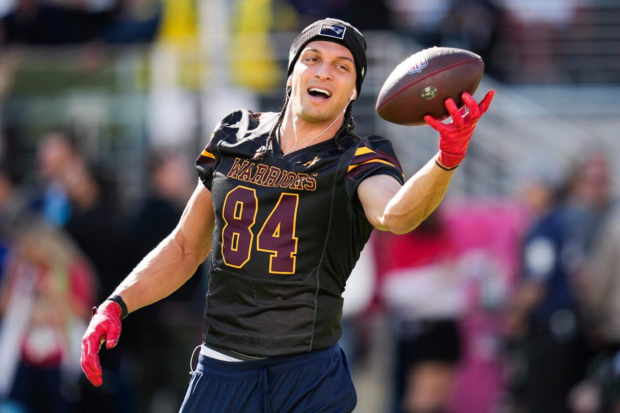 Mack Hollins smiles and makes a one-handed catch during warm-ups. He wears a black jersey with the number 84 in red.