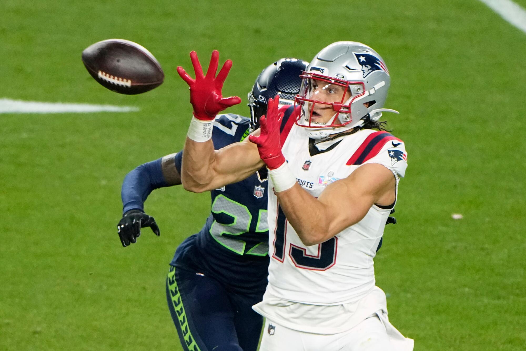 Mack Hollins lifts his arms to catch a football with Seattle's Riq Woolen behind him