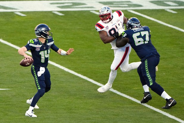 Seahawks quarterback Sam Darnold (14) drops back to pass as offensive tackle Charles Cross (67) defends against a rush by New England Patriots defensive end Milton Williams (97) during the first half of the Super Bowl on Sunday in Santa Clara, Calif. (AP Photo/Charlie Riedel)