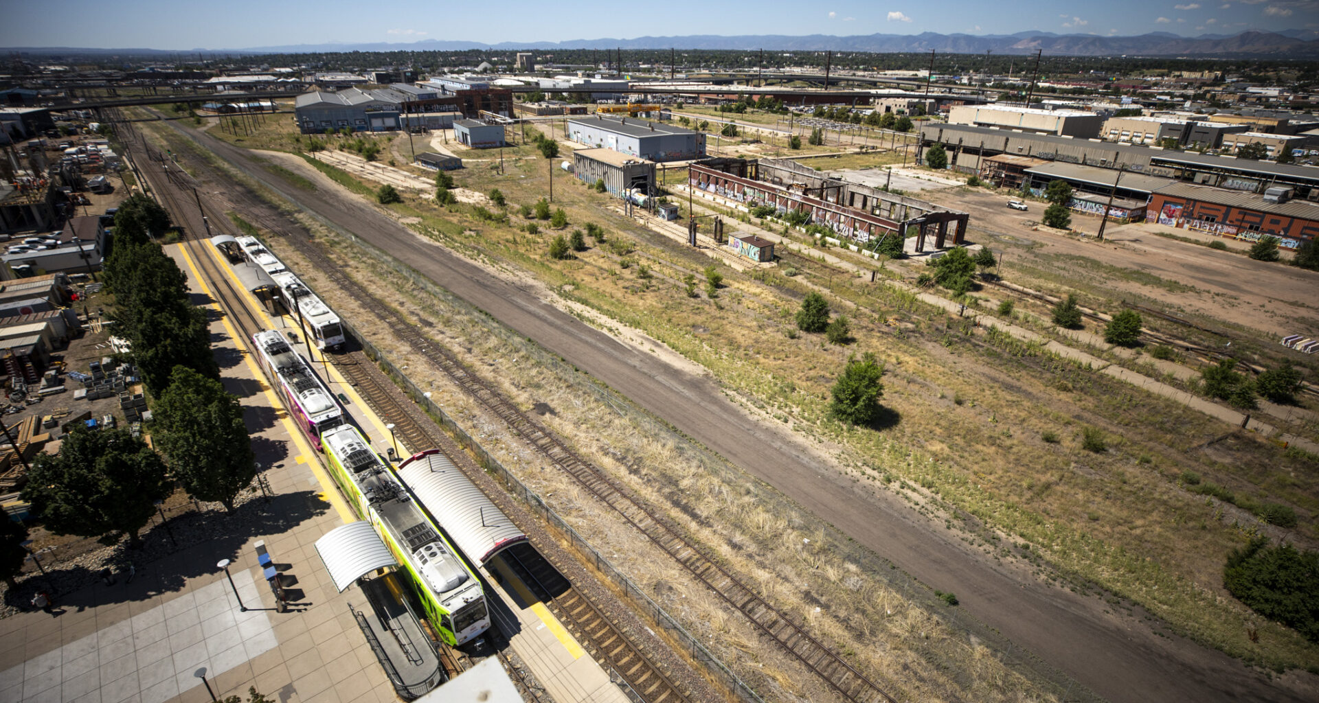 A group of people in hard hats fling shovels toward the sky as dirt rains down around them.