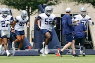 Dallas Cowboys guard Tyler Booker (52) warms up with other offensive players during an OTA...
