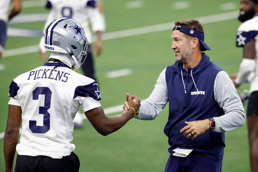 Dallas Cowboys head coach Brian Schottenheimer helps wide receiver George Pickens (3) to his...