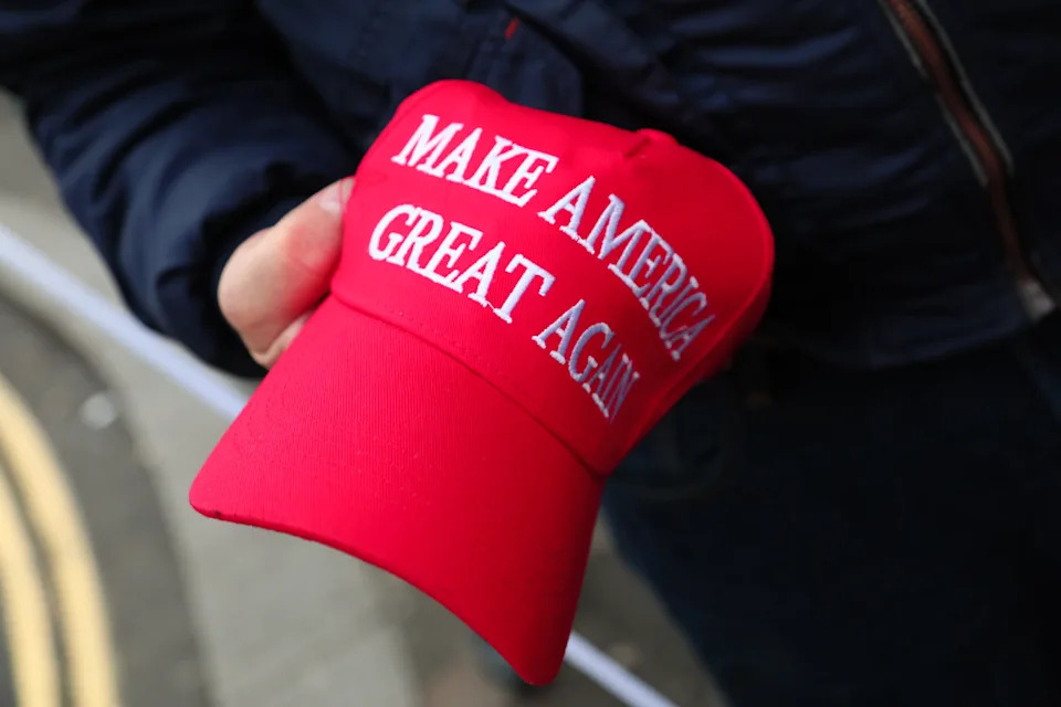 Red baseball cap with the slogan "Make America Great Again" held in a person's hand