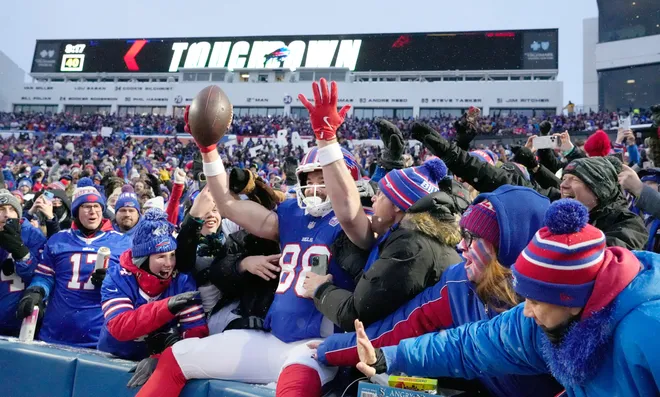 Bills tight end Dawson Knox leaps into the stands to celebrate with fans after scoring the opening touchdown of the game in first quarter against the Jets during the first half of their last regular season game at Highmark Stadium in Orchard Park Sunday, Jan. 4, 2026. The Bills won 35-8.