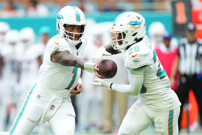 Nov 30, 2025; Miami Gardens, Florida, USA; Miami Dolphins quarterback Tua Tagovailoa (1) hands off to running back De'Von Achane (28) against the New Orleans Saints during the second half at Hard Rock Stadium. Mandatory Credit: Rich Storry-Imagn Images