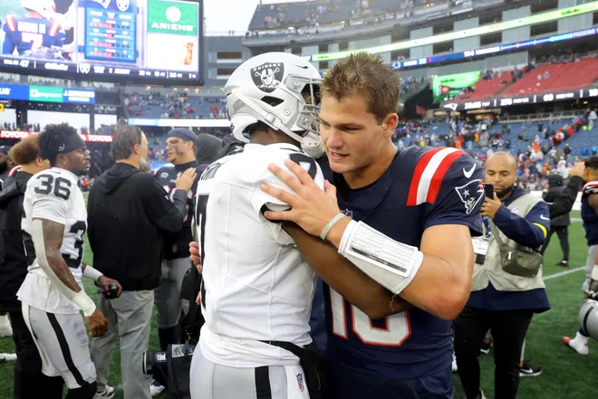 Drake Maye of the New England Patriots and Geno Smith of the Las Vegas Raiders embrace following the game at Gillette Stadium on September 7, 2025.
