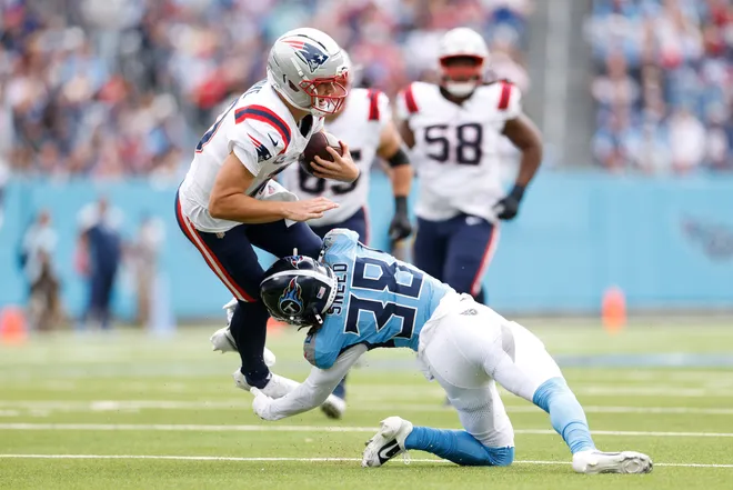 Drake Maye of the New England Patriots is tackled by L'Jarius Sneed of the Tennessee Titans.