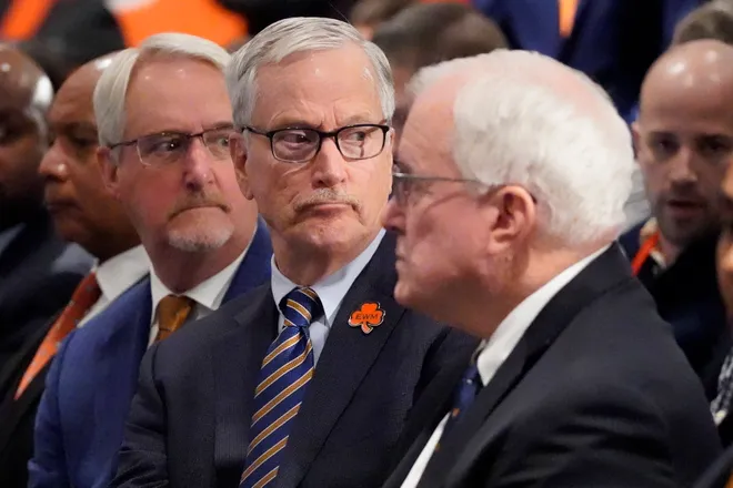Chicago Bears chairman George McCaskey (C) listens as new head coach Ben Johnson answers questions.