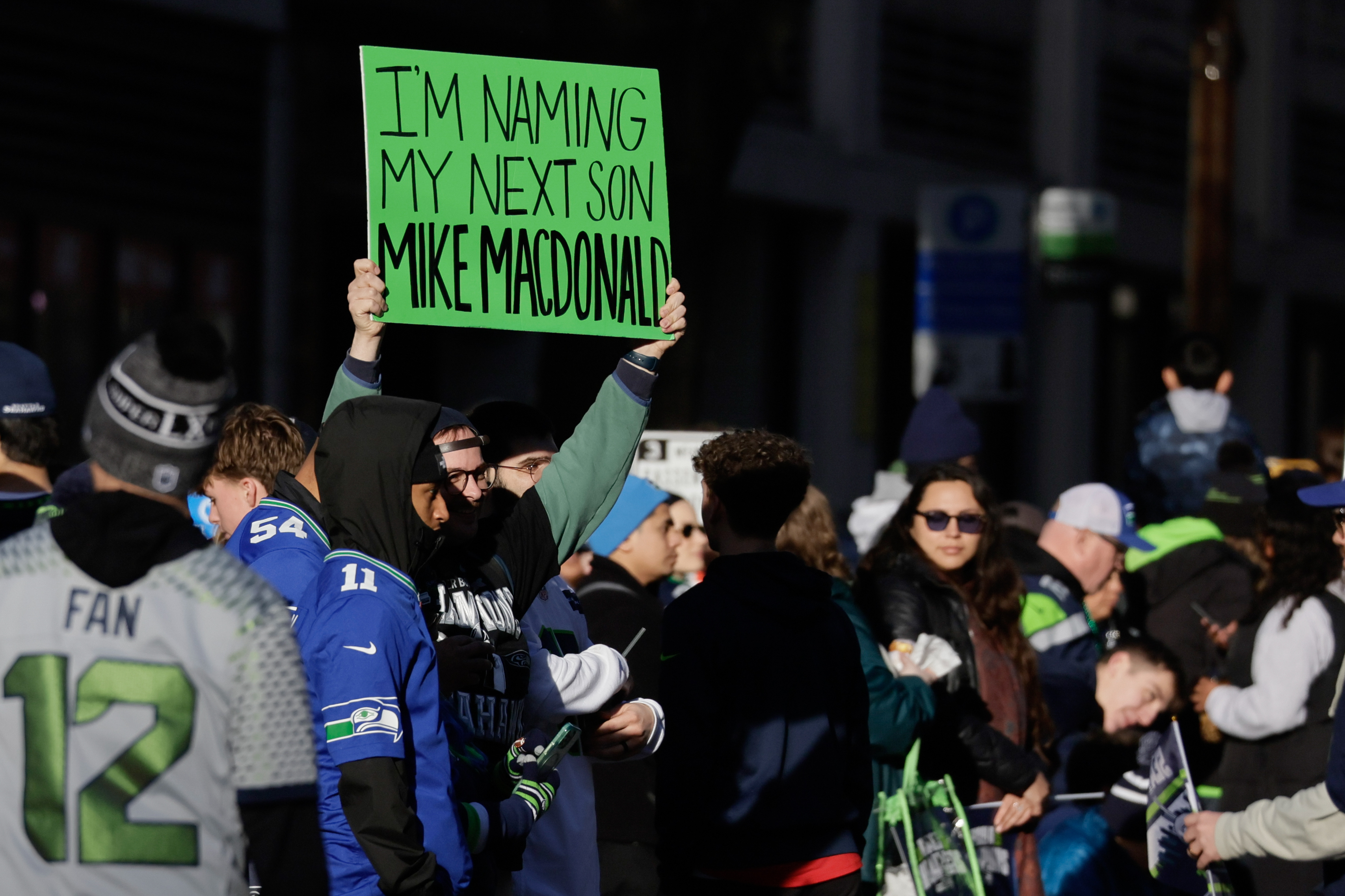 Someone holds a green sign which reads 'I'm naming my next son Mike McDonald'