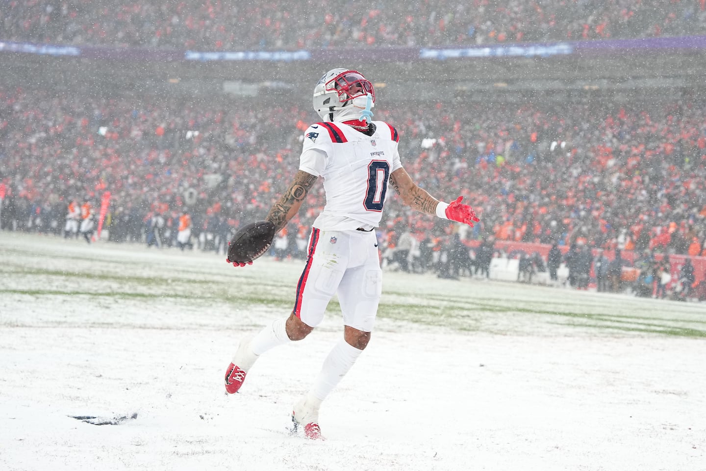 Christian Gonzalez celebrates in the snow after an interception that helped seal the Patriots’ victory in the AFC Championship game in Denver.