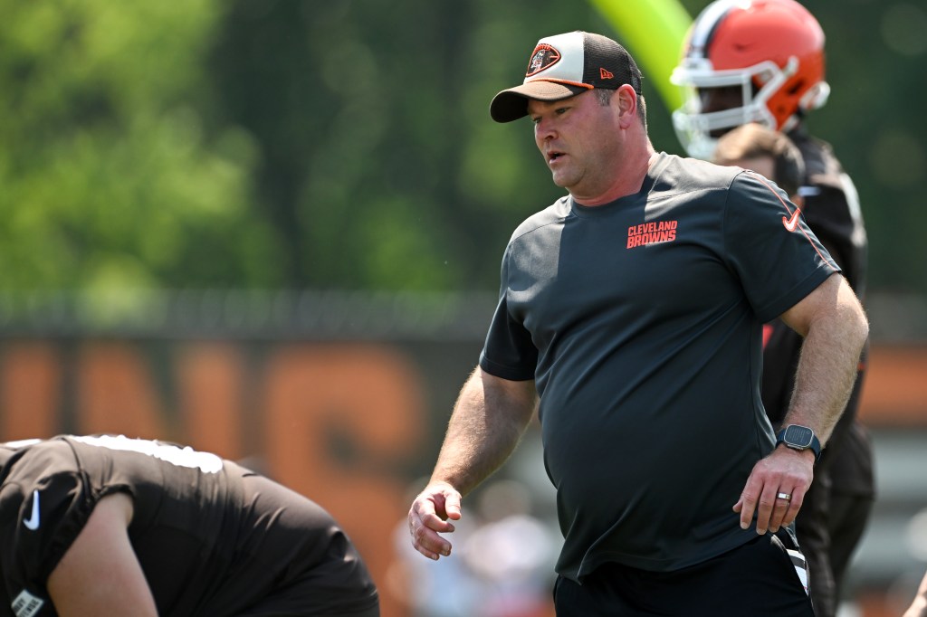 A man wearing a Cleveland Browns cap and shirt observing practice.