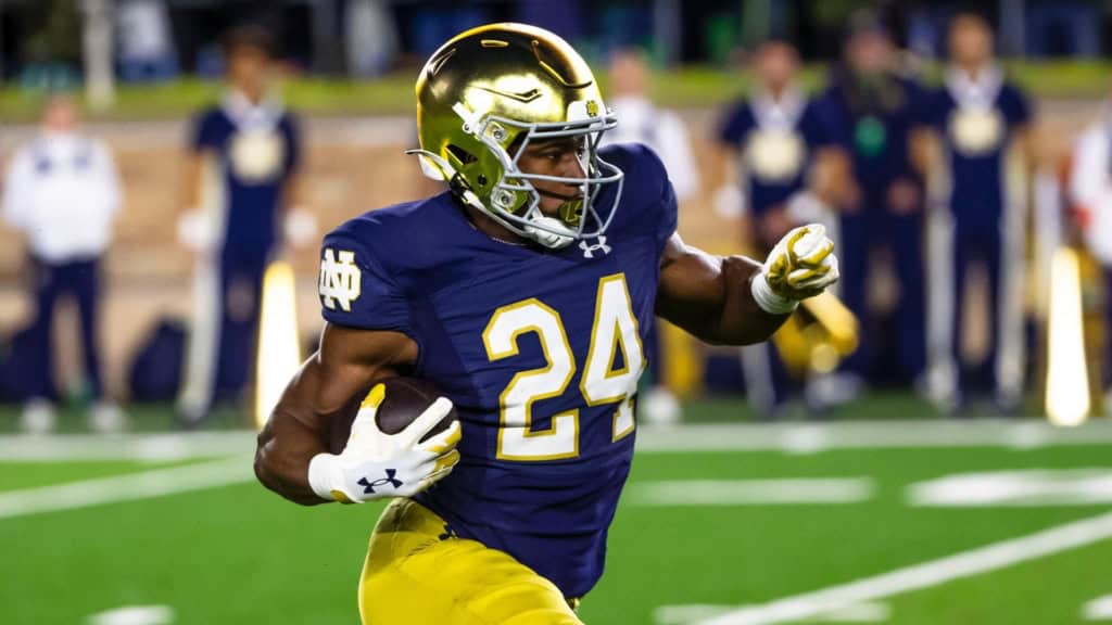 Jadarian Price runs with the football at Notre Dame Stadium, displaying vision and power in open space.