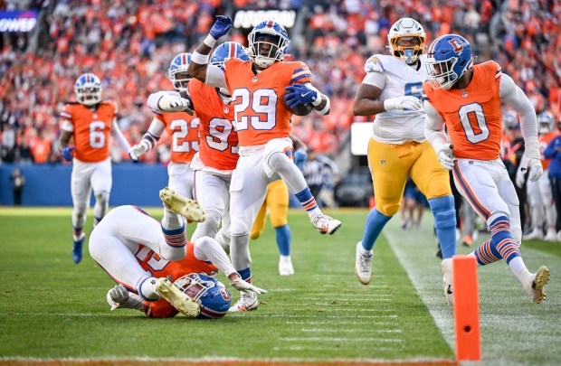 Ja'Quan McMillian (29) of the Denver Broncos leaps over Riley Moss (21) as he takes an interception on a ball thrown by Trey Lance (5) of the Los Angeles Chargers to the house during the first quarter at Empower Field at Mile High in Denver on Sunday, Jan. 4, 2026. (Photo by AAron Ontiveroz/The Denver Post)