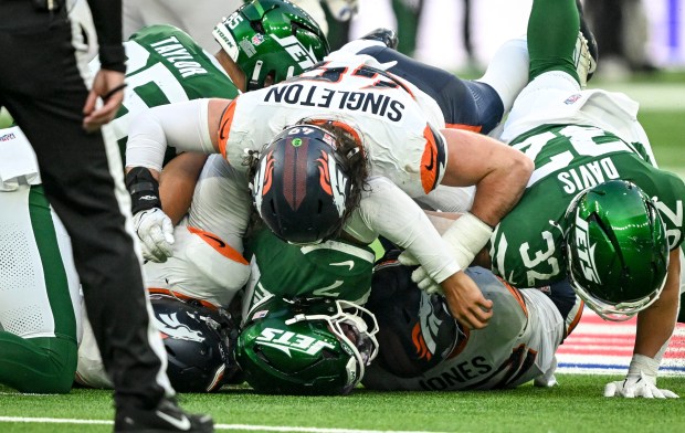 Alex Singleton (49) piles on Justin Fields (7) of the New York Jets after Jonathon Cooper (0) made a game-clinching sack during the fourth quarter of the Broncos' 13-11 win at Tottenham Hotspur Stadium in London on Sunday, Oct. 12, 2025. (Photo by AAron Ontiveroz/The Denver Post)