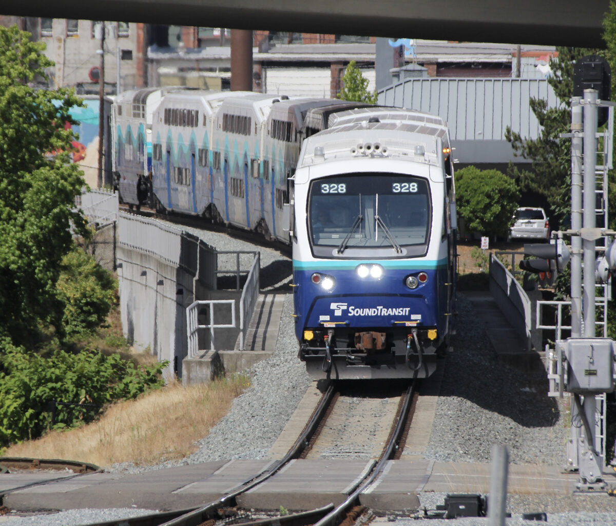 Blue and white commuter train approaches, led by cab car