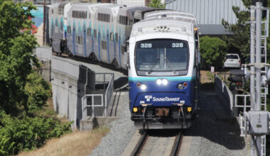 Blue and white commuter train approaches, led by cab car