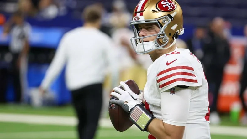 49ers quarterback Mac Jones warms up on the field at Lucas Oil Stadium before a game. Vikings QB target Mac Jones.