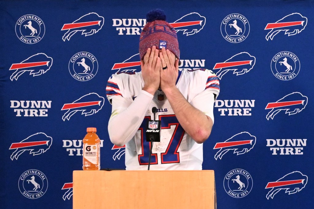 Buffalo Bills quarterback Josh Allen covers his face with his hands at a news conference.