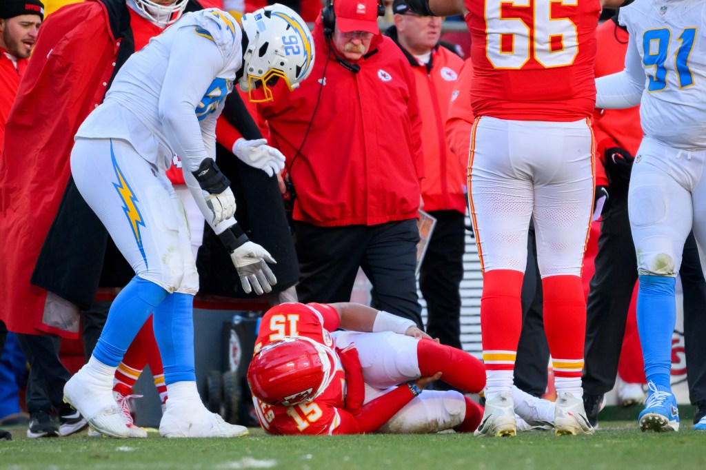Chargers defensive tackle Justin Eboigbe checks on injured Chiefs quarterback Patrick Mahomes as coach Andy Reid looks on.
