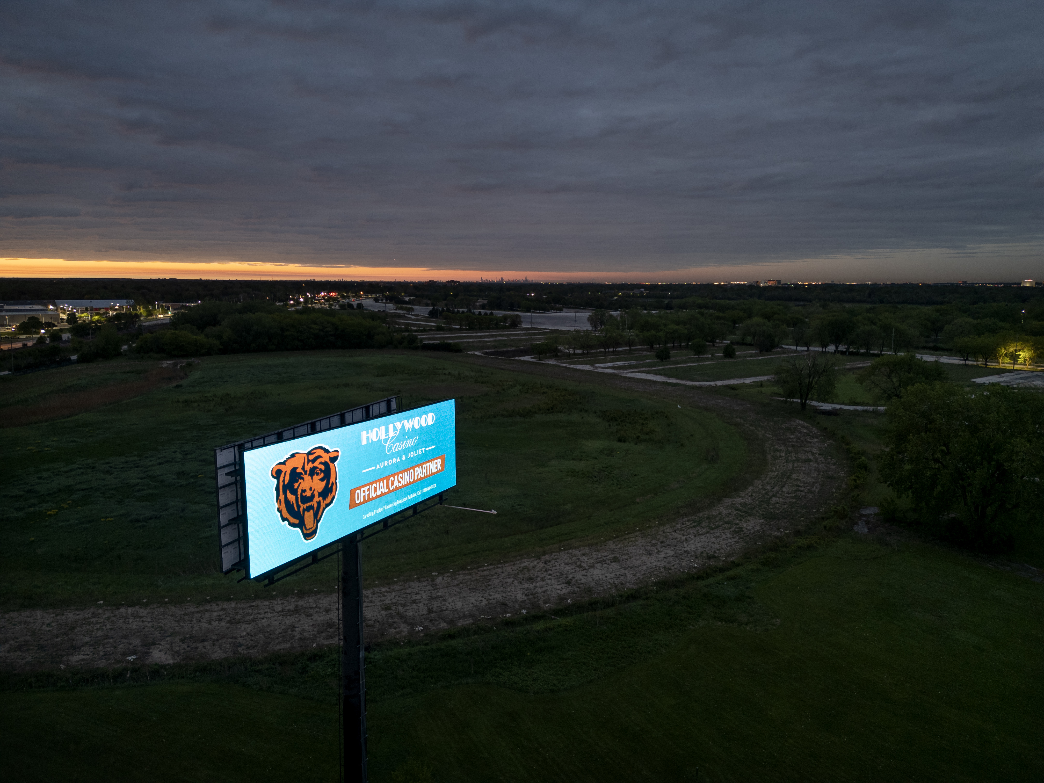 A Chicago Bears digital billboard glows at sunrise just off...