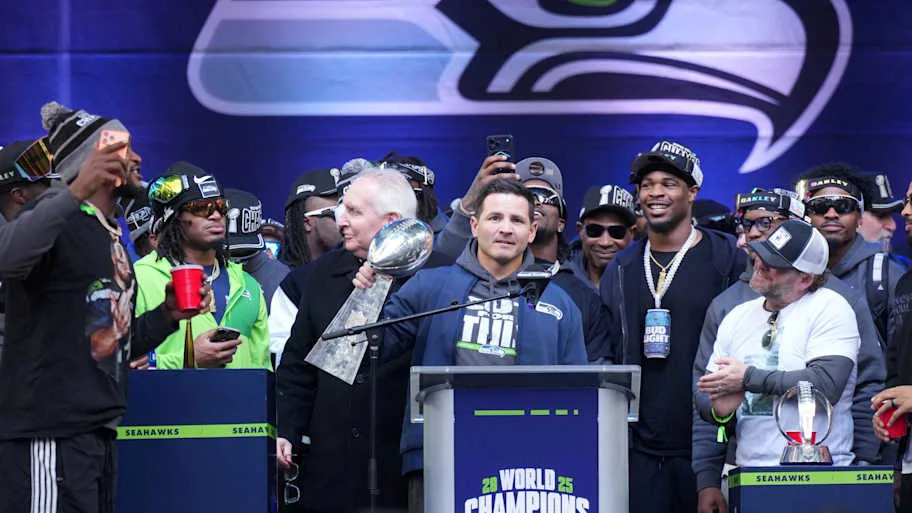 Seattle Seahawks head coach Mike MacDonald holds the Vince Lombardi trophy as general manager John Schneider watches