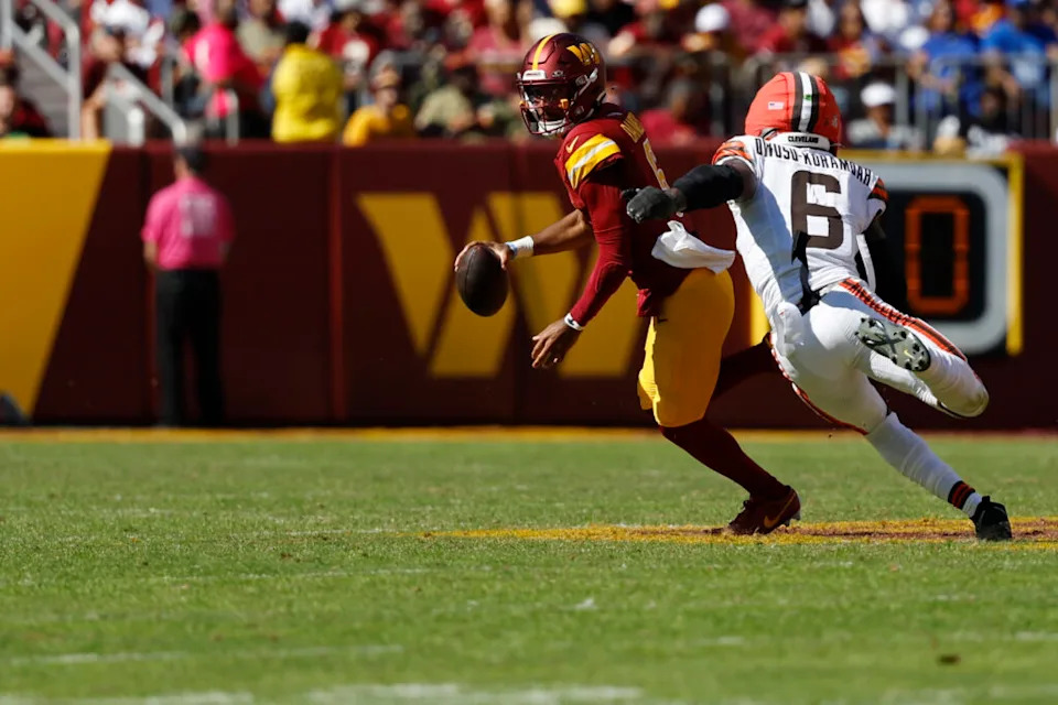 Oct 6, 2024; Landover, Maryland, USA; Washington Commanders quarterback Jayden Daniels (5) scrambles from Cleveland Browns linebacker Jeremiah Owusu-Koramoah (6) during the second quarter at NorthWest Stadium. Mandatory Credit: Geoff Burke-Imagn Images